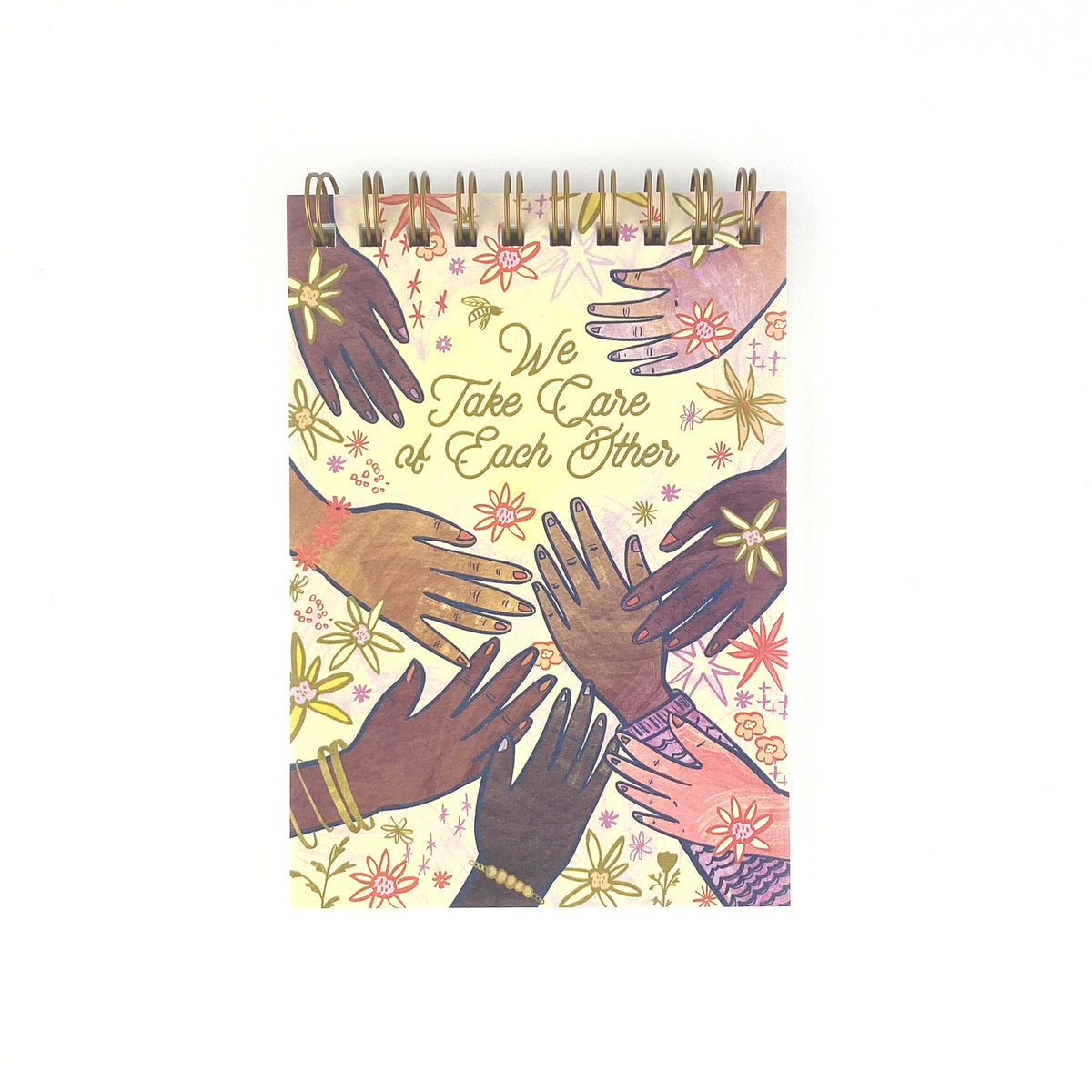 Spiral Bound notebook with hand drawn artwork of multi racial hands and flowers. In the center text says We Take Care of Each Other.