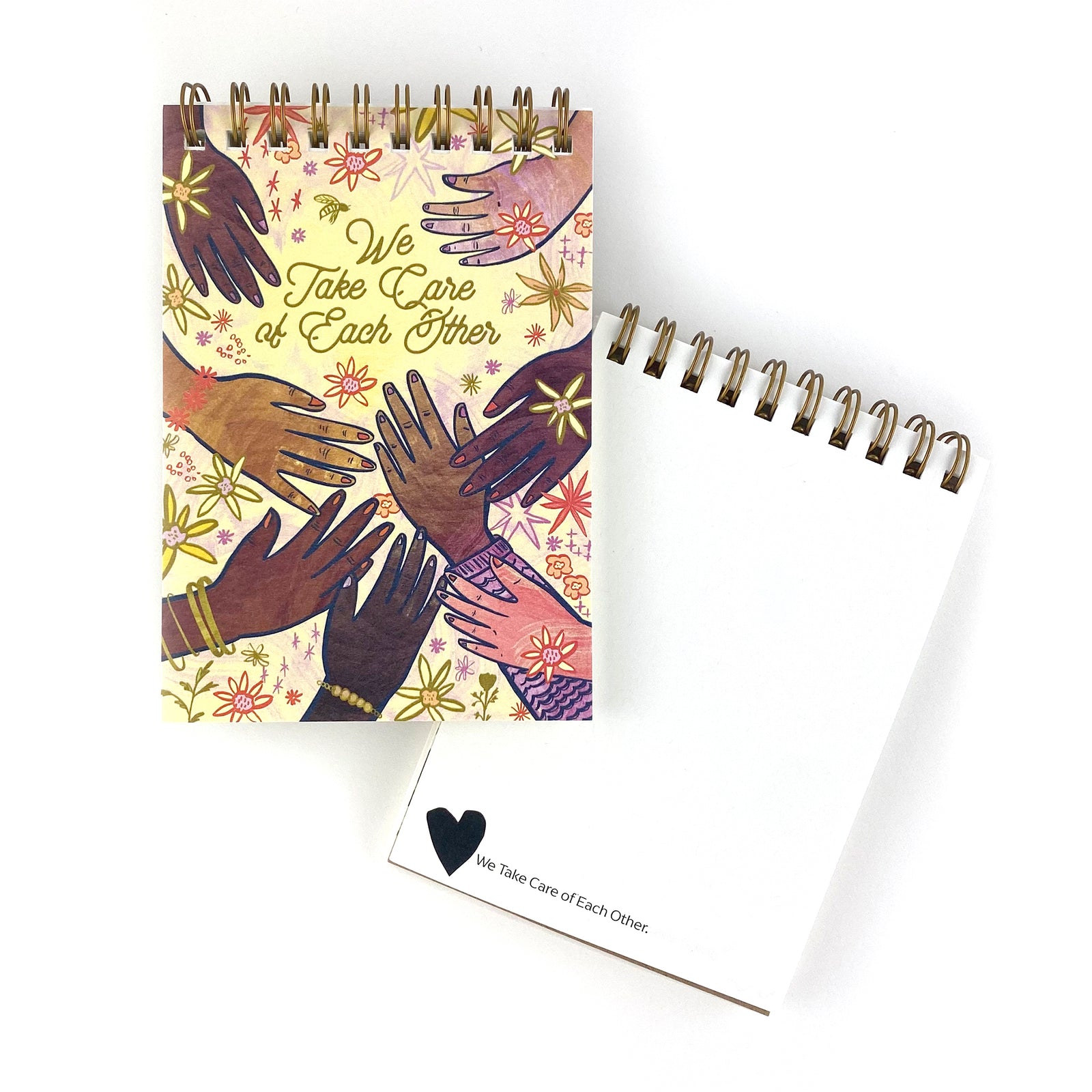 Spiral Bound notebook with hand drawn artwork of multi racial hands and flowers. In the center text says We Take Care of Each Other.