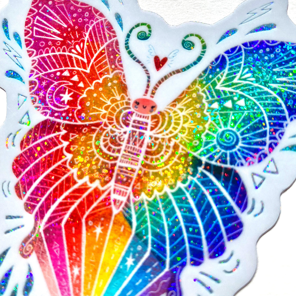 Butterfly shaped rainbow glitter sticker with white outline on a mint green background.